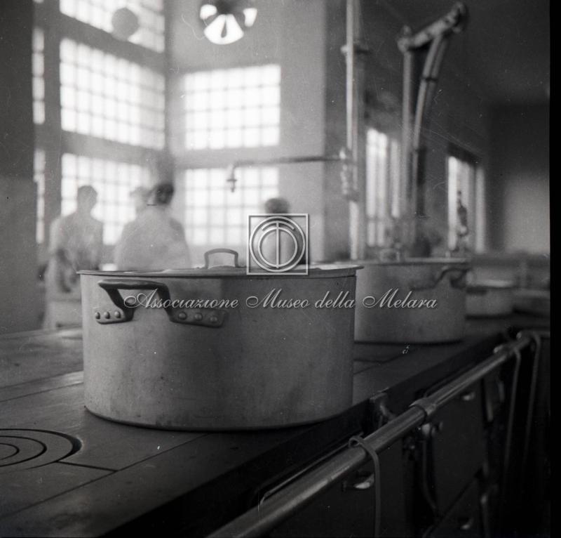 Pentole della cucina con cuochi sullo sfondo